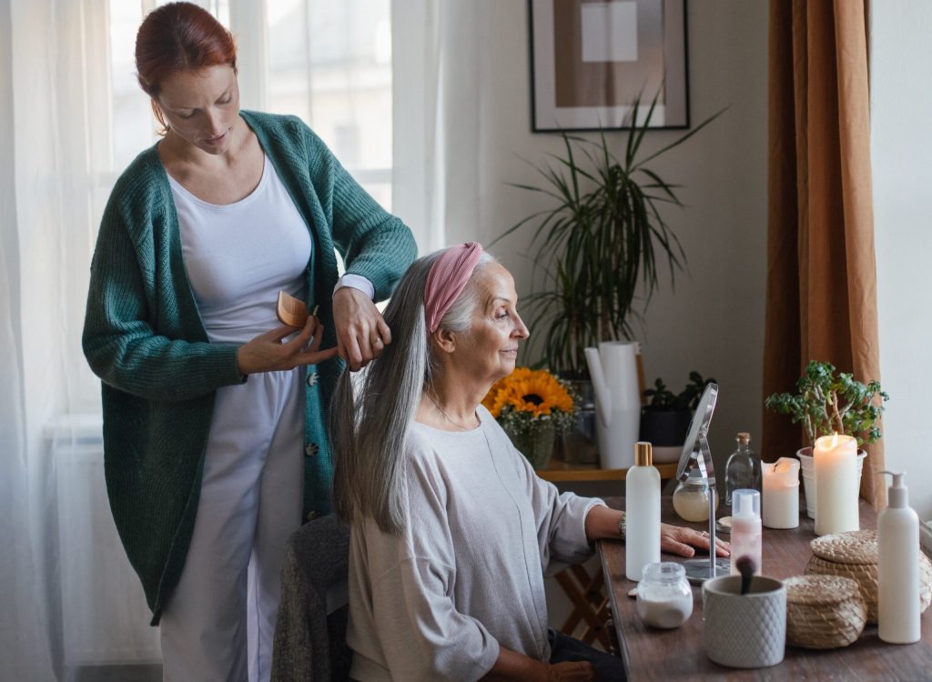 Caregiver helping her senior client with hairstyle.